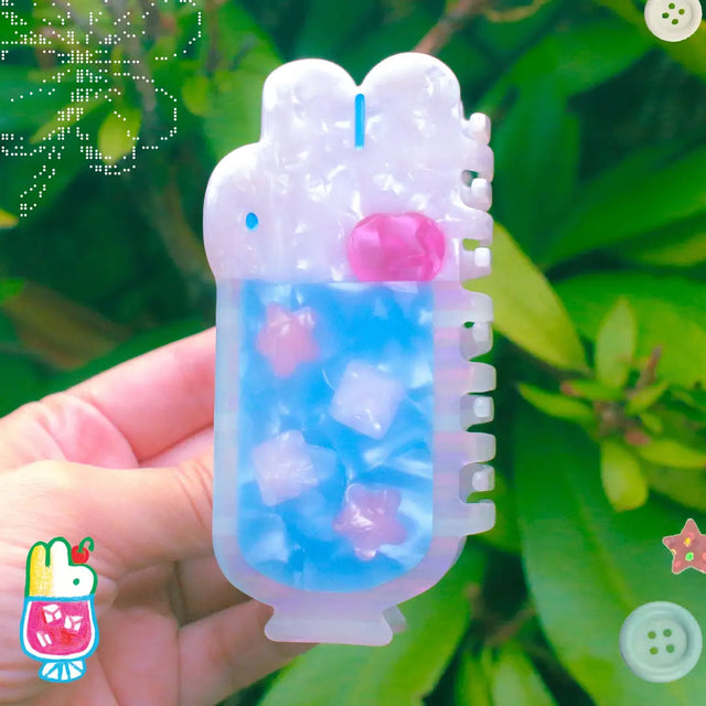 'Soda Float' Hair Claw featuring a blue soda float with rabbit shaped ice cream on top.

Made of acetate, 4 inches by 2 inches.

Hair claws come packaged in a plastic sleeve.