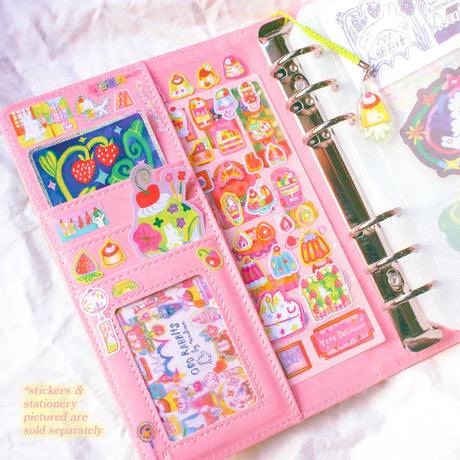 This is a A6 six ring binder that measures 14 cm x 19 cm when closed! It includes interior pockets for extra storage and a hole on the spine for charms.

This binder is great for storing stickers, sticker packs, note cards, photo cards, pet tape loops, ephemera and small sticker sheets. They can also be filled with paper and used as a notebook or journal.
