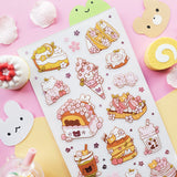 🌸🍰 Welcome springtime sweetness! This adorable sheet by @littlehecki is bursting with sakura magic and yummy café treats. From fluffy shortcakes and swirly cream rolls to dreamy parfaits, sakura cupcakes, and pastel milk teas, every dessert feels kissed by cherry blossoms. It’s like a cherry blossom picnic in sticker form — petals drifting through the air, sunshine on your cheeks, and sweet seasonal treats all around.

Art by: @littlehecki

Top Coating: None
Adhesive Layer: PVC (plastic)
Backing Layer: Cl