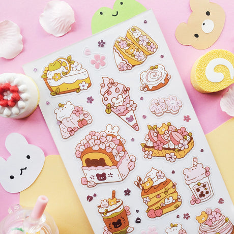 🌸🍰 Welcome springtime sweetness! This adorable sheet by @littlehecki is bursting with sakura magic and yummy café treats. From fluffy shortcakes and swirly cream rolls to dreamy parfaits, sakura cupcakes, and pastel milk teas, every dessert feels kissed by cherry blossoms. It’s like a cherry blossom picnic in sticker form — petals drifting through the air, sunshine on your cheeks, and sweet seasonal treats all around.

Art by: @littlehecki

Top Coating: None
Adhesive Layer: PVC (plastic)
Backing Layer: Cl
