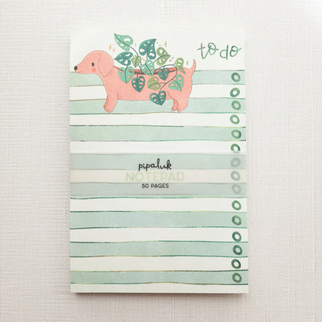 In a sunny Wildflower Woods cottage, a dachshund planter rests near a stack of well-loved books, leafy greens spilling gently from its back. This notepad brings that cozy, decorative moment to your desk, making everyday lists feel a little more inviting.

Designed to be practical without feeling busy, this notepad offers a simple, cheerful way to keep track of daily to-do lists and planning.