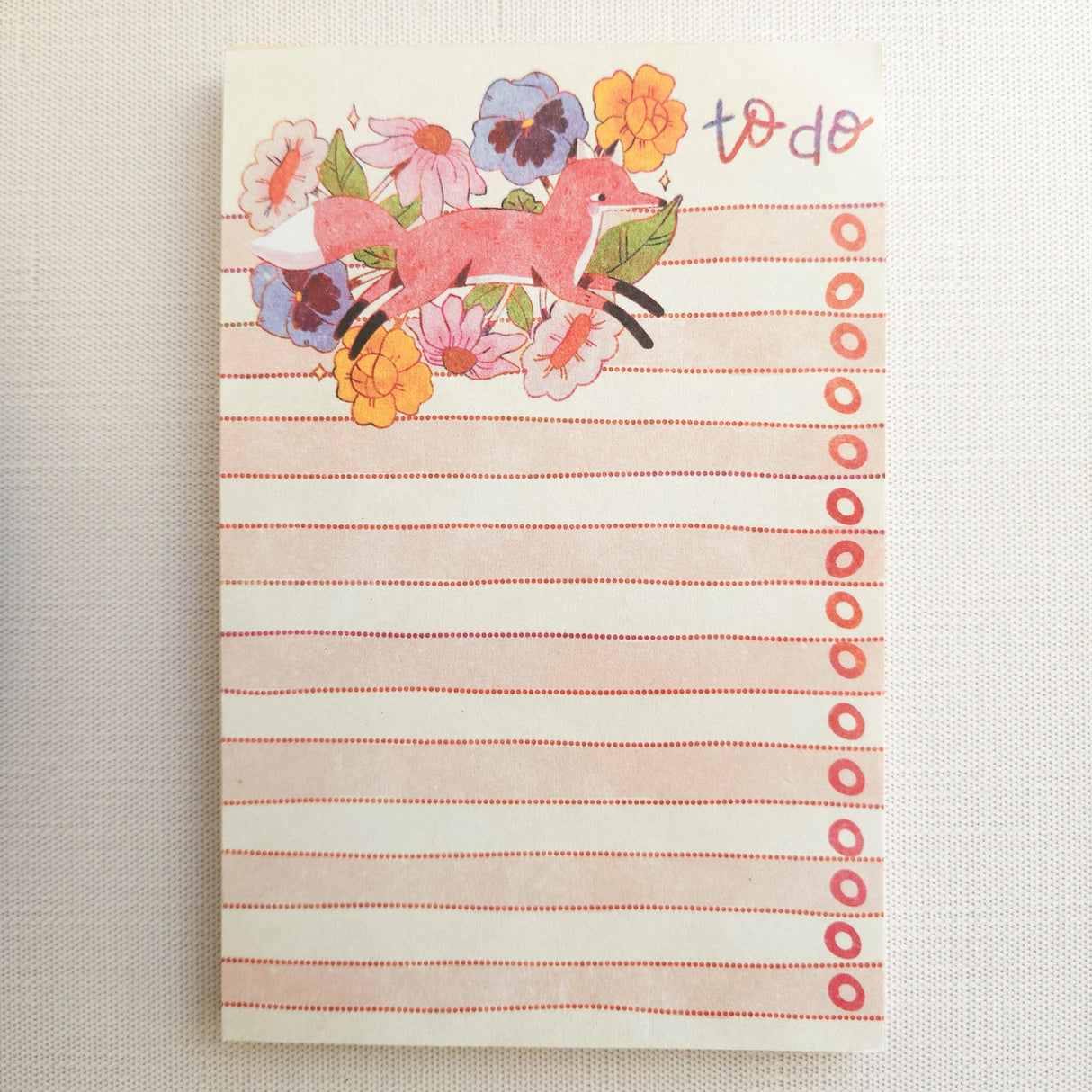 In a quiet clearing of Wildflower Woods, a fox moves through blooming flowers, petals lifting gently as he passes beneath open sky. This notepad brings that playful, woodland moment to your desk, making everyday lists feel a little more inviting.

Designed to be practical without feeling busy, this notepad offers a simple, cheerful way to keep track of daily to-do lists and planning.