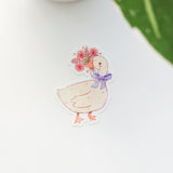 A sweet goose pauses with a bouquet of flowers held gently in its beak, a blue bow tied neatly at its neck. This vinyl sticker captures that charming, flower-filled moment, adding a warm, cottage-inspired touch to your everyday essentials.

Made from durable, waterproof vinyl, this sticker is designed to hold up wherever you place it—whether that’s a water bottle, laptop, or journal you reach for daily.