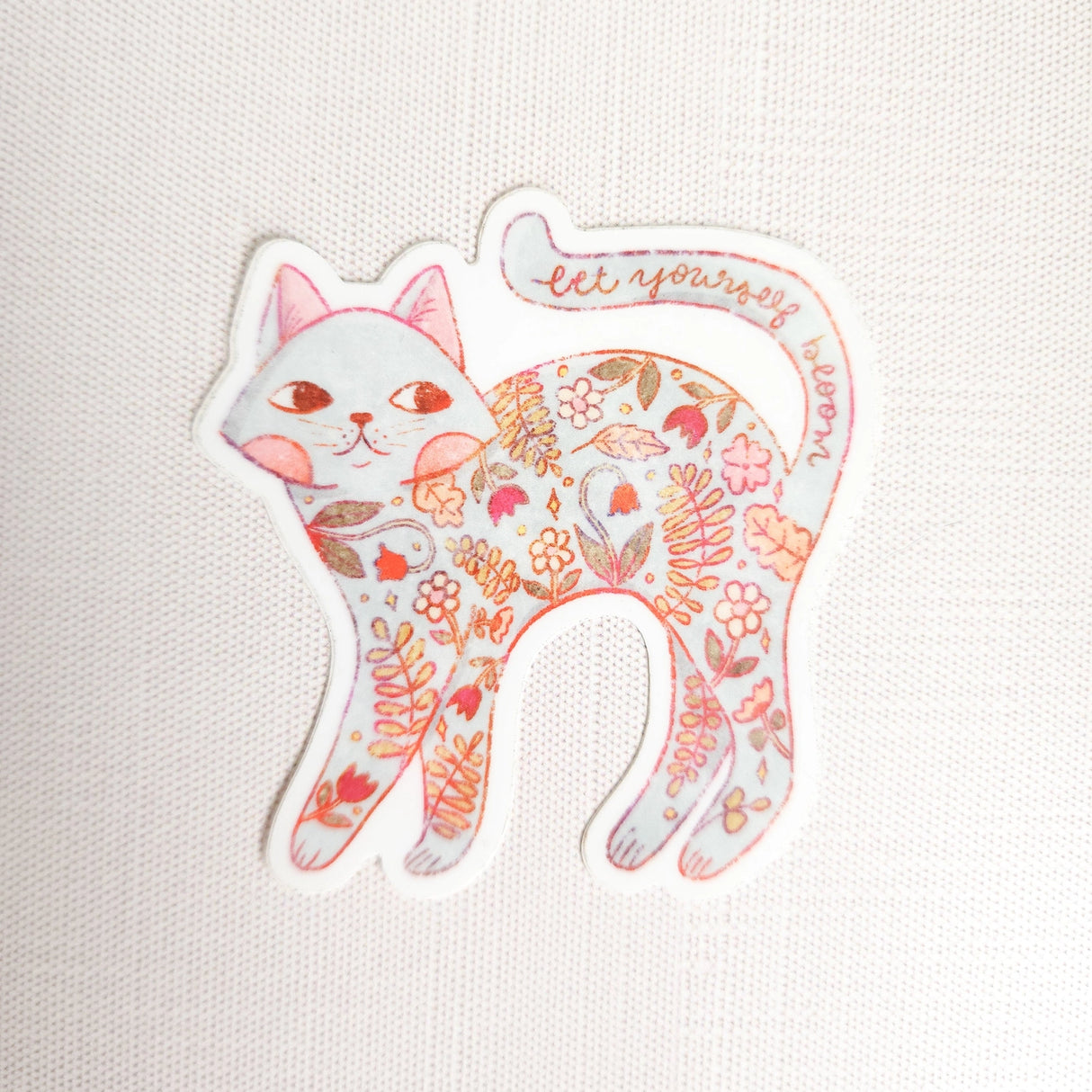 A calm cat returns from the blooming meadows of Wildflower Woods, patterned with flowers gathered along the way. This vinyl sticker captures that quiet, reflective moment, carrying a simple reminder to let yourself bloom.

Made from durable, waterproof vinyl, this sticker is designed to hold up wherever you place it—whether that’s a water bottle, laptop, or journal you reach for daily.