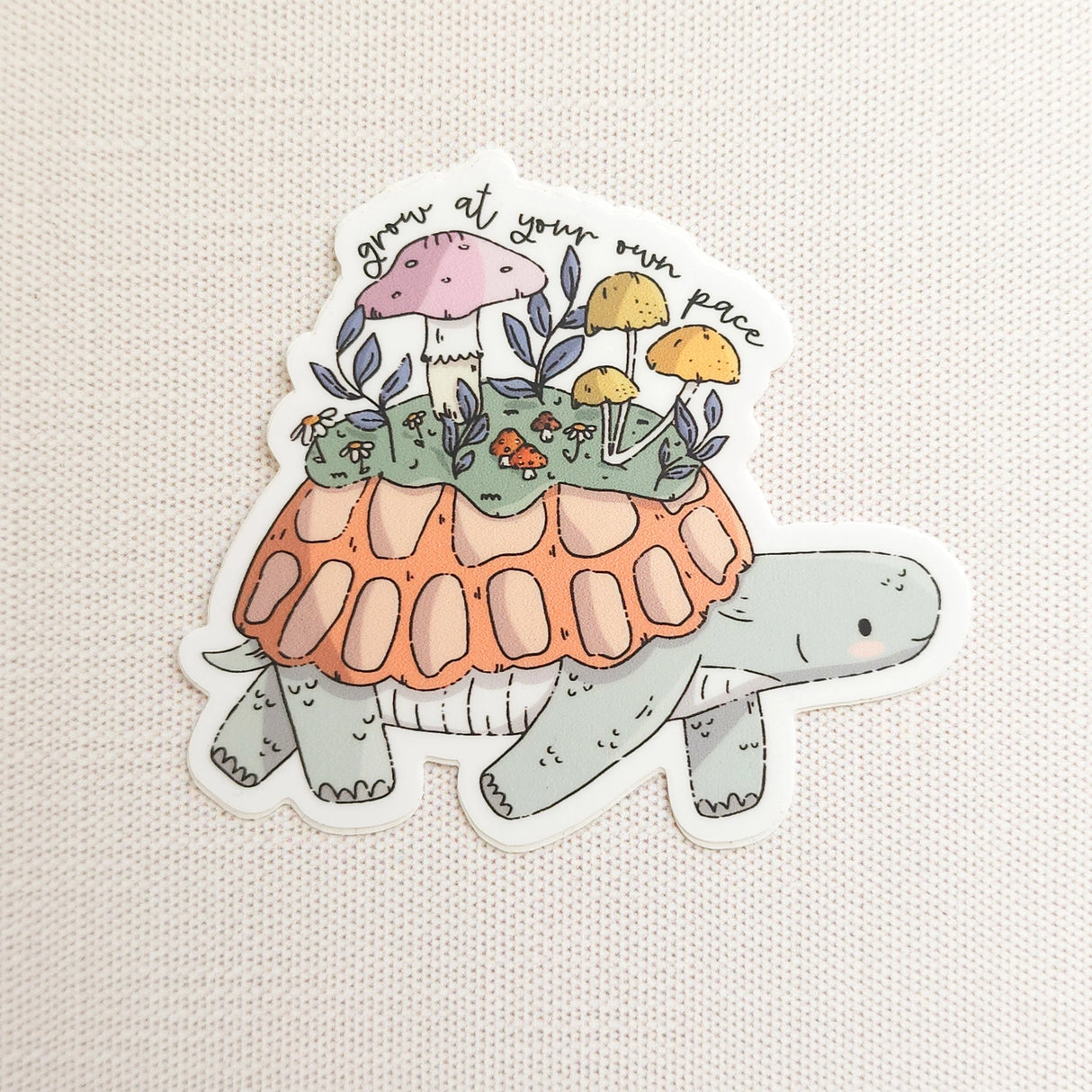 A turtle travels along a mossy path in Wildflower Woods, carrying a tiny mushroom meadow on its back as it moves steadily forward. This vinyl sticker captures that unhurried moment, carrying a gentle reminder that growth happens in its own time.

Made from durable, waterproof vinyl, this sticker is designed to hold up wherever you place it—whether that’s a water bottle, laptop, or journal you reach for daily.