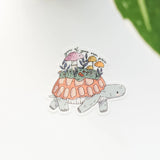 A turtle travels along a mossy path in Wildflower Woods, carrying a tiny mushroom meadow on its back as it moves steadily forward. This vinyl sticker captures that unhurried moment, carrying a gentle reminder that growth happens in its own time.

Made from durable, waterproof vinyl, this sticker is designed to hold up wherever you place it—whether that’s a water bottle, laptop, or journal you reach for daily.
