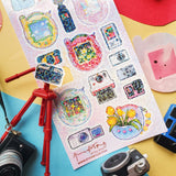 📸✨ Say cheese! From chunky digicams and instant printers to retro film cameras and pocket-sized pixel pets, this snap-happy sheet by @annadotpng is fully loaded with snapshot nostalgia. It’s a shutterbug’s dream, packed with dreamy screens and gadgets that totally flash back. Ready to capture some sticker magic? Point, shoot, print, repeat!

Art by: @annadotpng

Top Coating: Holo Glitter
Adhesive Layer: PVC (plastic)
Backing Layer: Clear PET
6.69" x 3.54".
Weight - 0.03lbs.
1 sheet included &nbsp; &nbsp;