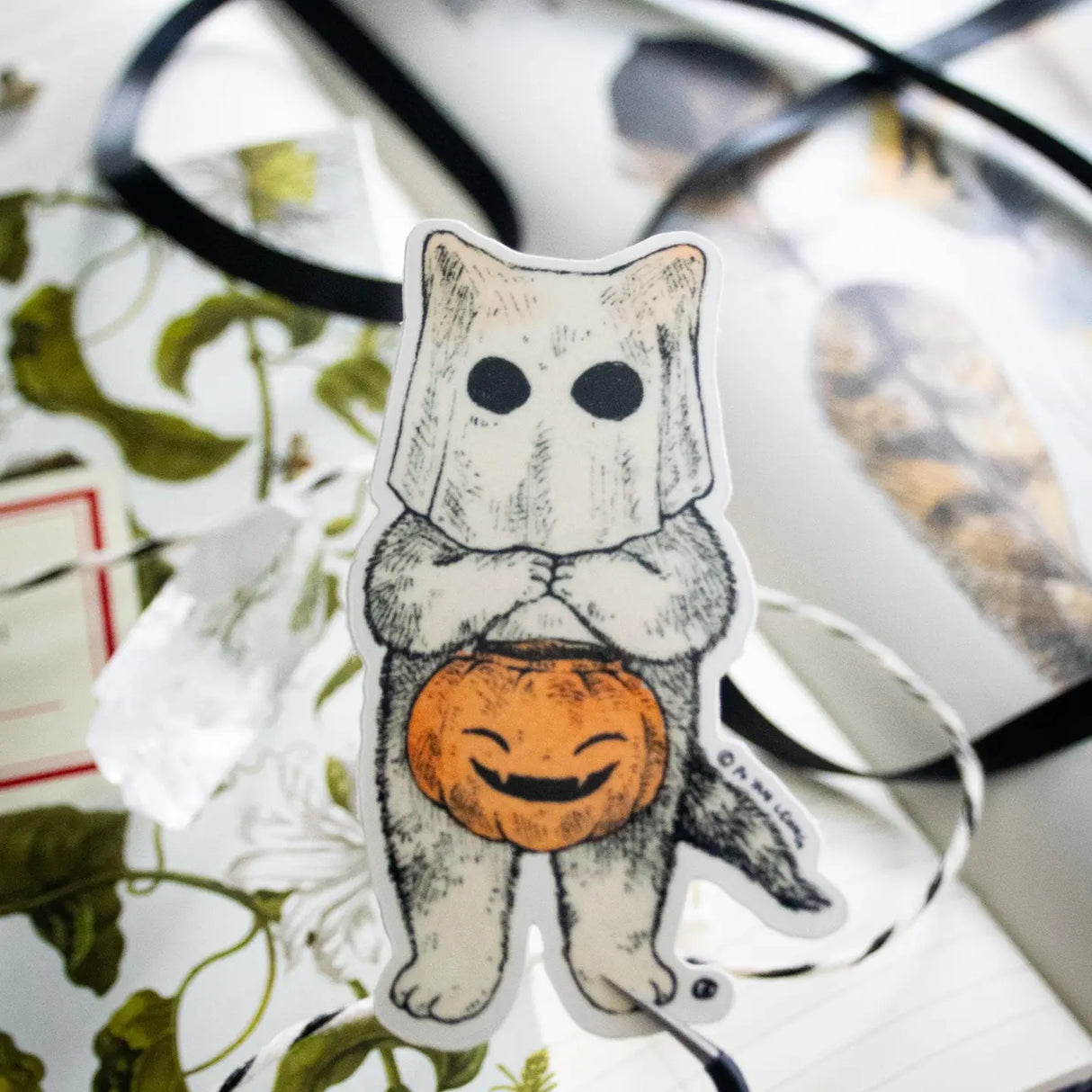 A cat dressed as a ghost for the spooky season, getting ready to go trick or treating! This whimsical illustration blends holiday spirit and magic, making it a perfect sticker for anyone who loves enchanting details. Printed on durable white vinyl, this sticker is waterproof, UV-proof, and made to last — ready to decorate laptops, journals, bottles, and more.