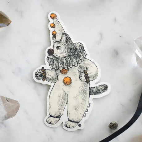 There's a kitty dressed as a clown going around looking for playful adventures. This whimsical illustration blends folklore and magic, making it a perfect sticker for anyone who loves enchanting details. Printed on durable white vinyl, this sticker is waterproof, UV-proof, and made to last — ready to decorate laptops, journals, bottles, and more.