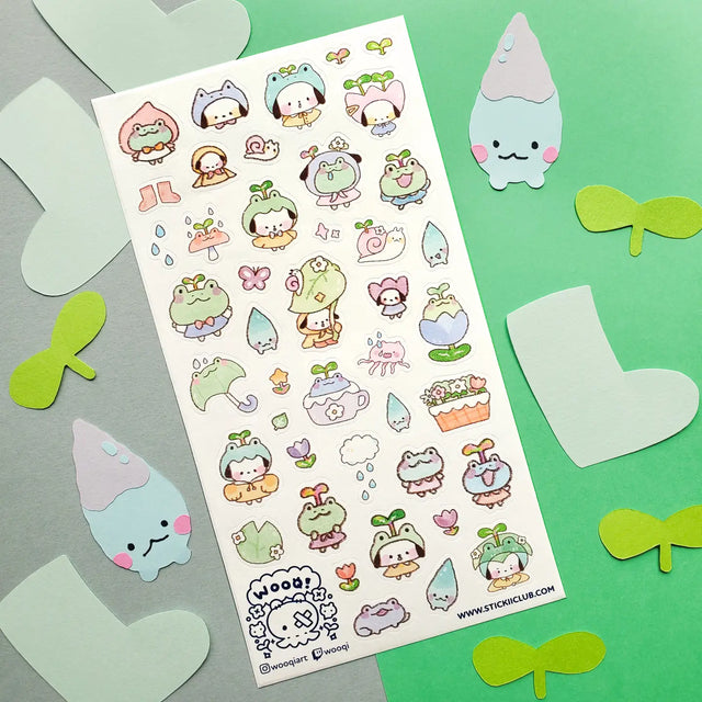 💧🌱 Spring is here, and a sprinkle of rain has brought @wooqiart’s kawaii garden to life! Cuties in froggy hoods and sprouty hats step out to enjoy the season among happy garden friends. With pastel raindrops, leafy umbrellas, and fresh flowers, we wish every drizzly day could be this adorable!