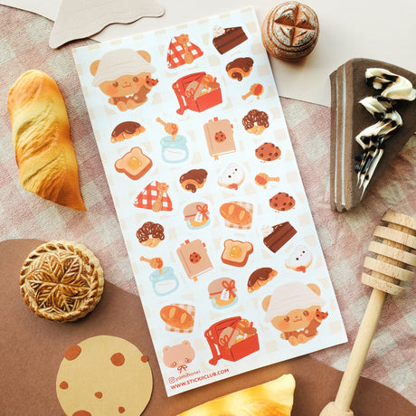 🧺🍯 Pack your blanket for the coziest little picnic! This darling sheet by @yomihonei is filled with flaky croissants, chocolatey buns, chunky cookies, golden loaves, buttery toast, and jars of honey all nestled on a gingham spread. With an adorable bear friend busy filling baskets and tying up tasty treats, it’s a kawaii afternoon of sunshine, crumbs, and cuddly bakery bliss. These stickers will add a drizzle of honeyed happiness wherever you stick them!

Art by: @yomihonei

Top Coating: None
Adhesive Lay