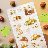 🌻🐝 Buzz on over to @bunnybee.garden’s whimsical garden, where chubby bunny-bees flutter through fields of flowers and cozy mushroom hideaways. From watering plants and zooming past blooming petals to splashing in puddles and snoozing in grassy corners, this sheet is bee-yond adorable.

Art by: @bunnybee.garden

Top Coating: None
Adhesive Layer: PVC (plastic)
Backing Layer: Clear PET
6.69" x 3.54".
Weight - 0.03lbs.
1 sheet included 