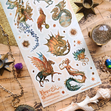 🦄🐉 Soaring through starlit skies and shimmering seas, @hopechristofferson’s mythical beings awaken a realm of untamed magic and ancient wonder. From a winged alicorn and celestial dragons to radiant sirens and cosmic creatures, get ready to weave epic fantasy tales and fill your pages with legendary beauty with this breathtaking sheet.

Art by: @hopechristofferson

Top Coating: Gold Foil
Adhesive Layer: Paper
Backing Layer: Paper
6.69" x 3.54".
Weight - 0.03lbs.