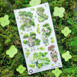 🌳🍃 Get ready to branch out with @maruti_bitamin’s bonsai beauties and leafy legends! These stylish forest guardians rock living tree crowns, flowing robes, and nature magic like it’s the hottest green trend of the season. Rooted in charm and bursting with botanical flair, this set is ready to sprout some serious wow on your pages!

Art by: @maruti_bitamin

Top Coating: None
Adhesive Layer: PVC (plastic)
Backing Layer: Clear PET
6.69" x 3.54".
Weight - 0.03lbs.
1 sheet included &nbsp; &nbsp;