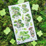 🌳🍃 Get ready to branch out with @maruti_bitamin’s bonsai beauties and leafy legends! These stylish forest guardians rock living tree crowns, flowing robes, and nature magic like it’s the hottest green trend of the season. Rooted in charm and bursting with botanical flair, this set is ready to sprout some serious wow on your pages!

Art by: @maruti_bitamin

Top Coating: None
Adhesive Layer: PVC (plastic)
Backing Layer: Clear PET
6.69" x 3.54".
Weight - 0.03lbs.
1 sheet included &nbsp; &nbsp;