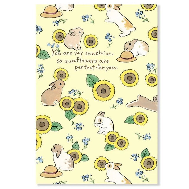 Hop into summer with this adorable postcard by Schinako Moriyama, who is known for her fun and adorable bunny scenes! This postcard features bunnies playing amongst the sunflowers.

4in x 5.8in