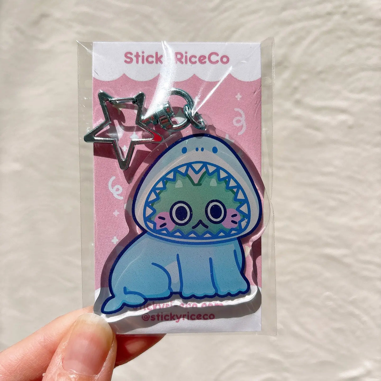 This shark cat keychain is the perfect accessory to your phone, purse, backpack, etc!

PLEASE NOTE: There may be plastic film covers on the backs of the keychains. The film is there to protect the keychains in transit and may look scratched. They can be removed to show shine/clarity on the surface.

Details:

2" in wide&nbsp;
ONE SIDED glitter epoxy with flat back&nbsp;
Double sided printing on sturdy acrylic&nbsp;
Colors may differ from picture due to lighting differences&nbsp;
Made in United States