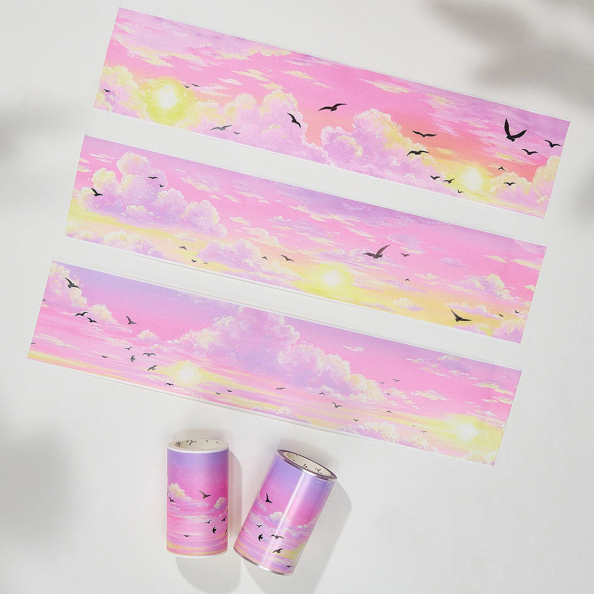 Capture the gentle embrace of evening with the Lotus Twilight Wide Washi/PET Tape. This tape embodies the softest part of the sunset. The design features a dreamy, seamless gradient that flows from a warm, glowing orange into a hazy, light lavender. Drifting through this pastel sky is a flock of silhouetted birds, gliding peacefully on the breeze. It brings a sense of calm and whimsy to your journal, perfectly replicating that quiet, cotton-candy sky moment just before the stars come out.