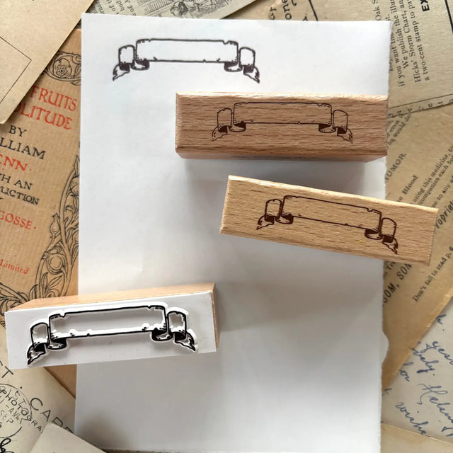 One rubber stamp of a banner! Use this for anywhere you need a fancy label for something.

Each stamp is made with beech wood and measures roughly 1.5L x .625W x .8H" (63x18x20mm). The stamp impression is 50mm wide, and the writable area on the scroll is 34mm wide.