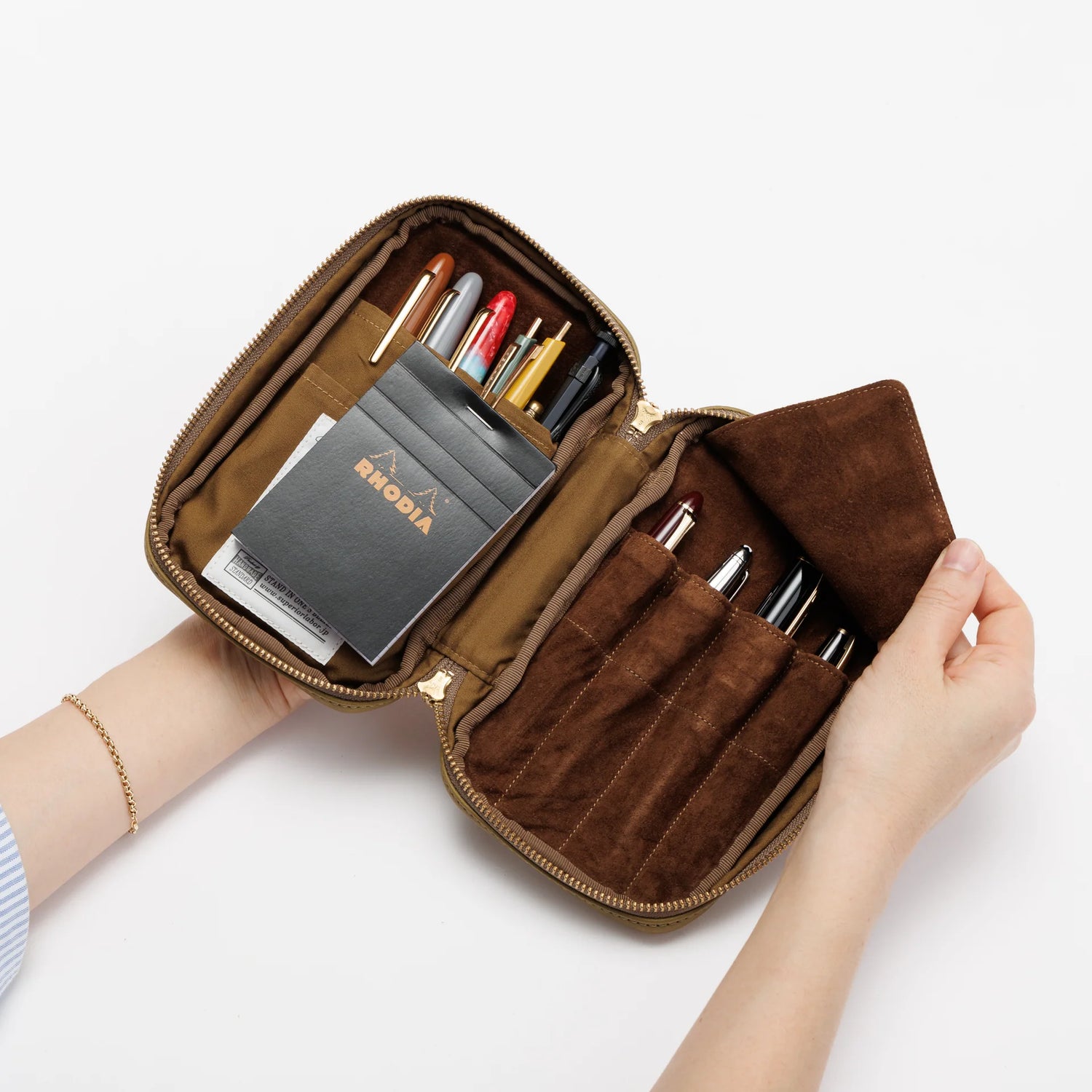 We crafted this leather case for those who love to write —for people who value the quiet moments spent with pen and paper.

Open it up, and on the right side, every surface that touches your precious pens is lined with soft suede, gently protecting them from scratches.&nbsp;On the left, two rows of pockets hold your memo pads, casual pens, or other writing companions, keeping everything neatly in place and ready whenever inspiration strikes.

Size: W13×H20×D4.5cm
About the Leather – Japanese Glove Leather

