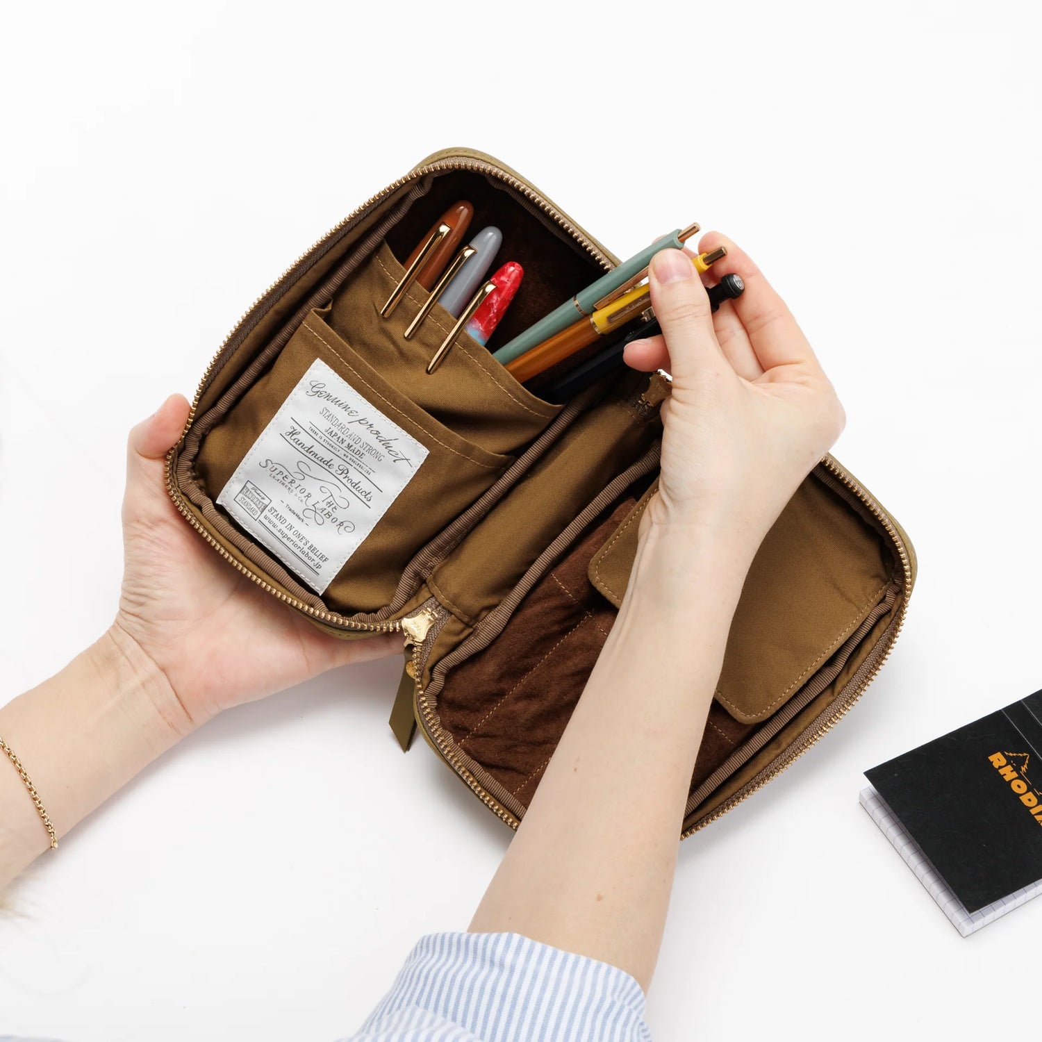 We crafted this leather case for those who love to write —for people who value the quiet moments spent with pen and paper.

Open it up, and on the right side, every surface that touches your precious pens is lined with soft suede, gently protecting them from scratches.&nbsp;On the left, two rows of pockets hold your memo pads, casual pens, or other writing companions, keeping everything neatly in place and ready whenever inspiration strikes.

Size: W13×H20×D4.5cm
About the Leather – Japanese Glove Leather

