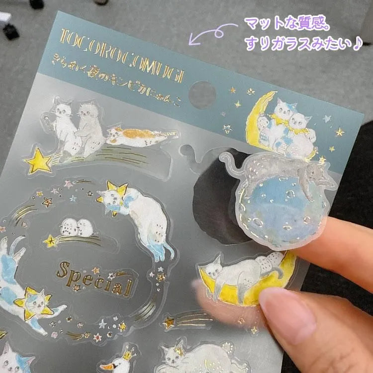 A sticker sheet with cute cats exploring and resting all throughout the starry night designed by Tokoro Komugi who is known for their soft style of illustration featuring animals! Perfect for decorating letters, notebooks, and more!