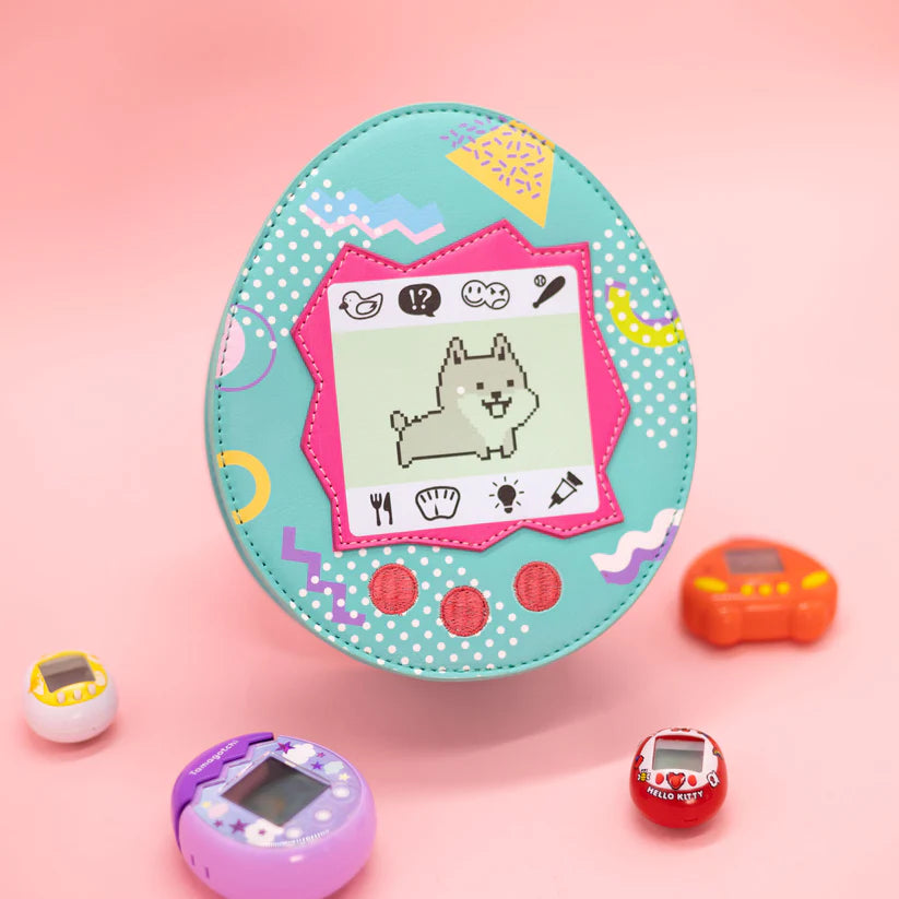 Throwback to the Tamagotchi days! Did you own a virtual pet back in the day? If not, do not worry, we got you covered. Available in cat or dog.  Features a zipper closure and adjustable strap.

Dimensions: 7.25” x 3” x 8.5”