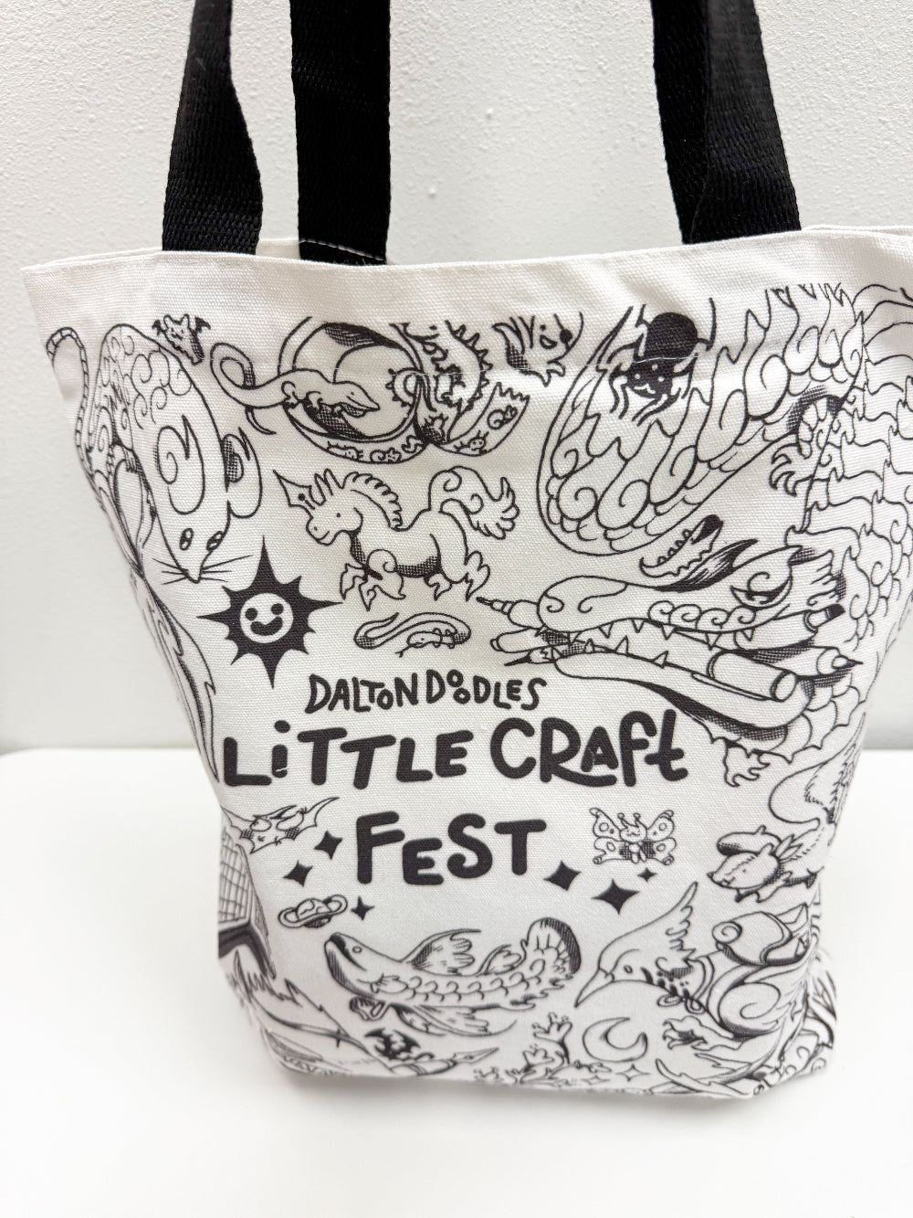 Carry a little magic everywhere you go.  
This exclusive Little Craft Fest x Dalton Doodles tote bag celebrates the debut of Dalton’s newest universe, a whimsical world where everyday stationery transforms into mystical creatures. Featuring Dalton’s first sketch from the series, this tote brings charm, creativity, and a spark of imagination to your daily routine.