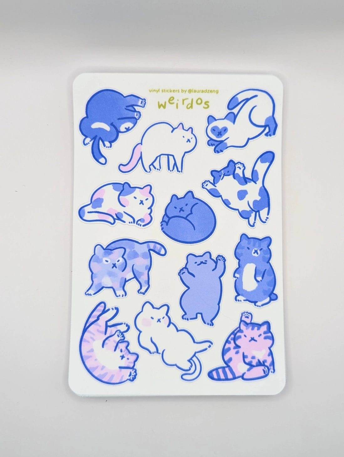 Featuring 12 adorably pudgy cats, each one sporting its own quirky personality, this 4"x6" vinyl sticker sheet is perfect for adding a touch of whimsy to your everyday items. From the cat who’s too cool for school to the one who’s just a little bit offbeat, these weirdos celebrate the joy of being different.